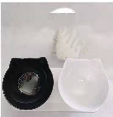 Two cat-shaped bowls, one black and one white, on a white background.